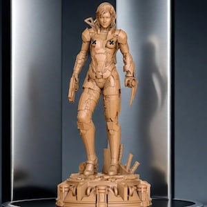 May include: A tan-colored figurine of a female figure in futuristic armor, holding a gun and a blade. The figure stands on a detailed base with architectural elements. The armor has cross-shaped markings on the chest.