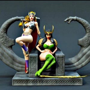 May include: A detailed figurine set featuring two characters: one standing with blonde hair, a silver winged helmet, and a red cape, and another seated on a grey stone throne with black hair, a gold horned headpiece, and green attire.