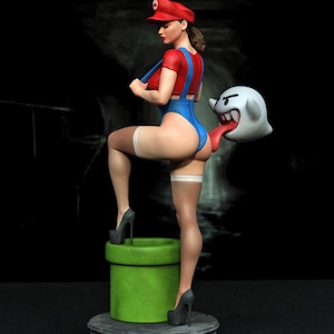 May include: A figurine of a character wearing a red cap, red shirt, and blue overalls, standing on a green pipe. The character wears white thigh-high stockings and grey high heels. A white ghost figure with a red tongue is positioned behind.