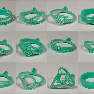 May include: A collection of twelve turquoise ring molds in various designs. Each ring mold features unique shapes, including geometric, floral, and abstract patterns. The molds are made of a smooth, plastic-like material.