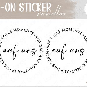 Könnte beinhalten: Zwei runde Rub-On-Sticker mit schwarzem Text auf weißem Hintergrund. In der Mitte steht "auf uns" in Schreibschrift, umgeben von dem kreisförmigen Text "AUF TOLLE MOMENTE AUF DAS WAS KOMMT AUF DAS LEBEN" mit kleinen Herzsymbolen.
