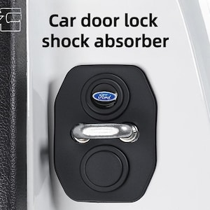 Könnte beinhalten: Ein schwarzer Autotürschloss-Stoßdämpfer mit einem metallisch silbernen Riegel und einem kleinen blau-weißen Ford-Logo. Der Text Car door lock shock absorber steht über dem Bauteil, das an einer weißen Fahrzeugverkleidung montiert ist.