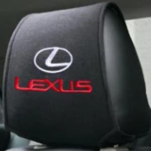 Puede incluir: Una funda negra para reposacabezas de coche que presenta el logotipo blanco de Lexus en la parte superior y la palabra LEXUS bordada en letras rojas justo debajo. La funda está hecha de un material de tela suave y oscuro para el reposacabezas.