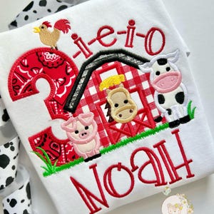 May include: A white onesie with red embroidered text that says " -i-e-i-o Noah" and a red and white checkered barn with a pig, horse, cow, and rooster.