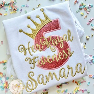 Peut inclure: T-shirt blanc avec broderie dor&eacute;e qui dit "Her Royal Fiveness Samara" avec un chiffre 5 rose paillet&eacute; et une couronne dor&eacute;e au-dessus du chiffre.