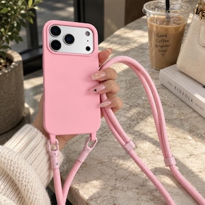 Op de afbeelding: Een effen lichtroze smartphonehoesje met een rechthoekige uitsparing voor de camera en een bijpassend roze gevlochten koord, bevestigd aan de onderste hoeken met twee metalen sluitingen om het apparaat over de schouder te dragen.
