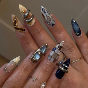 Uñas postizas estilo gótico oscuro cyberpunk, uñas stiletto metálicas 3D, uñas con estampado abstracto, uñas de gel estilo punk vanguardista, uñas de lujo para chicas modernas.