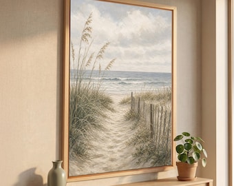 May include: A framed vertical wall art print depicting a sandy beach path leading to the ocean. The scene features tall beach grass, a weathered wooden fence, and a cloudy sky in muted tones of beige, green, and soft blue, displayed on a console.