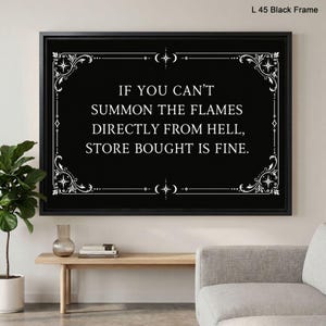 May include: A rectangular wall art piece in a black frame featuring a black background with white decorative filigree corners and borders. The text reads: IF YOU CAN'T SUMMON THE FLAMES DIRECTLY FROM HELL, STORE BOUGHT IS FINE. L 45 Black Frame.