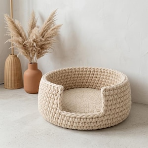 Può includere: Un letto rotondo per animali domestici all'uncinetto beige con un morbido cuscino color crema. Il letto ha un fronte basso e aperto per un facile accesso ed è realizzato con filato spesso e strutturato. Per piccoli animali domestici.