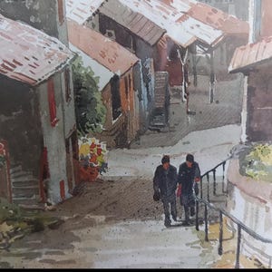 Puede incluir: Pintura a la acuarela de una escena de pueblo europeo. Dos figuras caminan por un camino de piedra con una barandilla de metal. Los edificios con tejados de tejas rojas y marcos de ventanas rojas bordean la calle. La obra de arte tiene una paleta de colores apagados.