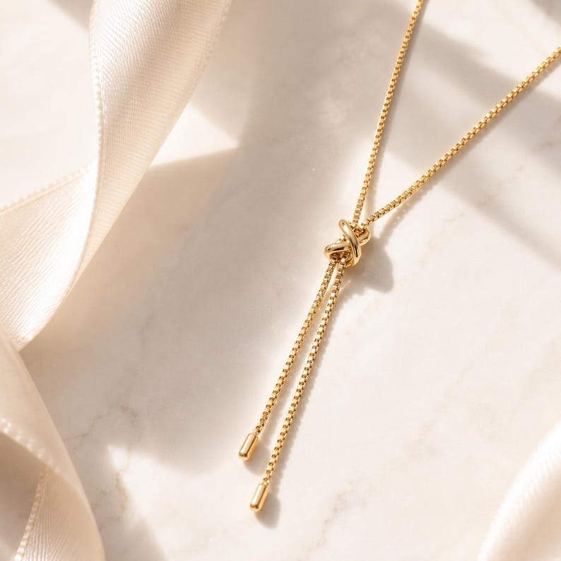 Dainty 18K gold PVD bolo necklace with an adjustable sliding chain, polished minimalist finish, and delicate drop ends.