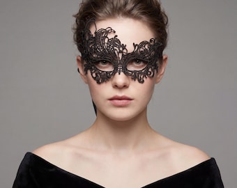 Könnte beinhalten: Eine schwarze Spitzen-Maskenmaske mit einem komplizierten floralen Design. Die Maske bedeckt die Augen und weist zarte, wirbelnde Muster auf. Die Maske wird von einer Person getragen, die ein schwarzes schulterfreies Oberteil trägt.