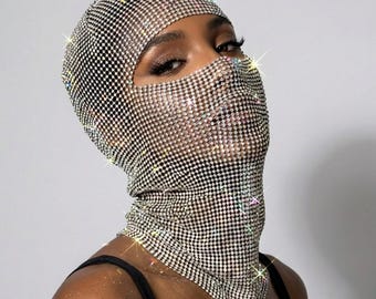 May include: A full-head balaclava mask constructed from a flexible mesh material densely covered in small, reflective silver rhinestones. The headpiece features a single large opening for the eyes and nose, providing a shimmering, metallic appearance.