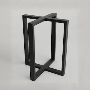 Puede incluir: Una base de mesa de metal negro mate con un diseño robusto en forma de cruz tanto en la parte superior como en la inferior. La estructura consta de cuatro soportes verticales rectangulares conectados por barras horizontales.