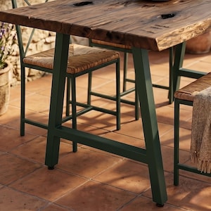 May include: A dining set featuring a rectangular table with a dark brown wood grain top and a natural live edge, supported by dark green metal A-frame legs. The matching chairs have dark green metal frames and woven tan seats.