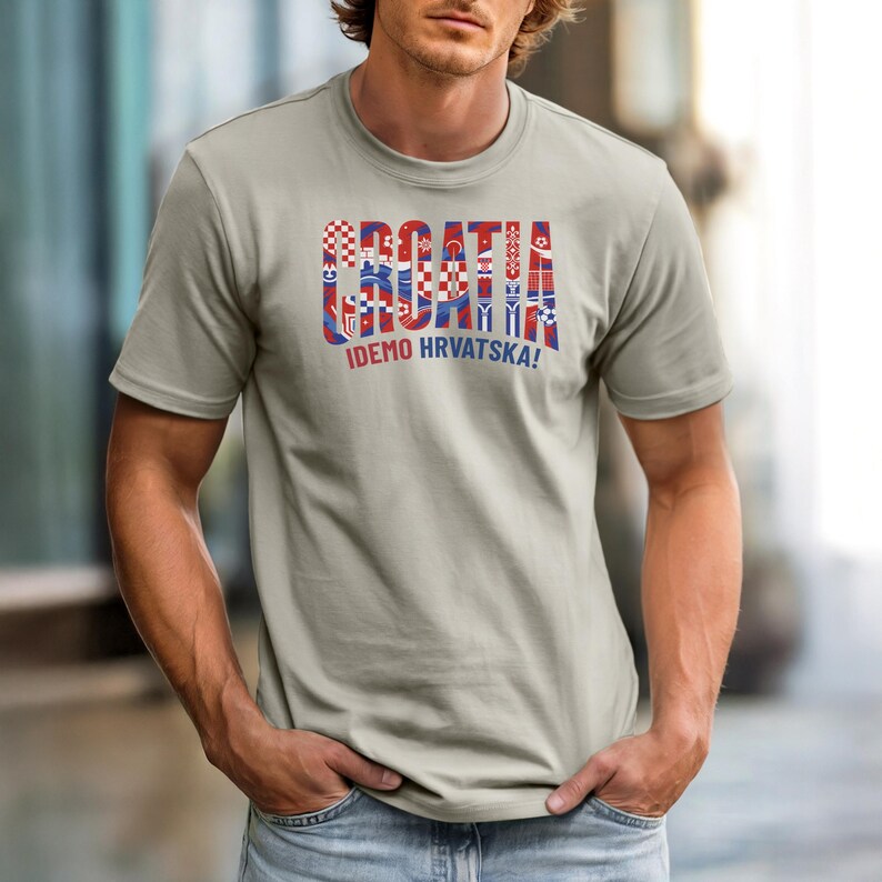 May include: A light gray t-shirt with the word "CROATIA" in red, white, and blue, with various Croatian flag-inspired designs within the letters. Below the word is the text "IDEMO HRVATSKA!"