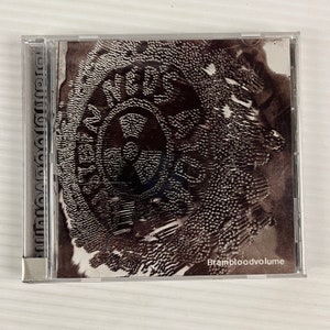 May include: A black and white CD case with a black and white image of a circle with the word "BRAMBLED" inside. The text "Brambloodvolume" is printed in white at the bottom of the case.