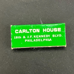 Peut inclure: Une petite boîte d'allumettes rectangulaire avec un fond vert vif. Le texte "CARLTON HOUSE" est imprimé en blanc, ainsi que l'adresse "18th & J.F. KENNEDY BLVD. PHILADELPHIA".
