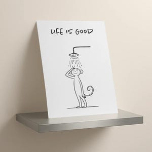 May include: A white art print featuring a cartoon monkey enjoying a shower. The print has the words "LIFE IS GOOD" at the top. The monkey is drawn in black ink, with a simple, minimalist style.