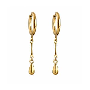 May include: A pair of gold-toned hoop earrings featuring a dangling vertical bar attachment that ends in a smooth, polished teardrop-shaped charm. The earrings have a reflective metallic finish and a simple, clean design with a secure hinged closure.