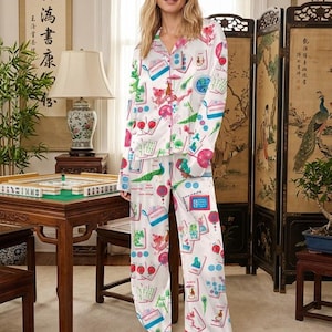 K&ouml;nnte beinhalten: Wei&szlig;es Satin-Pyjama-Set mit farbenfrohem Mahjong-Fliesen-Print. Das lang&auml;rmlige Oberteil und die Hose haben ein Hemd mit Kn&ouml;pfen und eine lockere Passform. Der Druck enth&auml;lt Illustrationen von Drachen, Pfauen und Laternen.