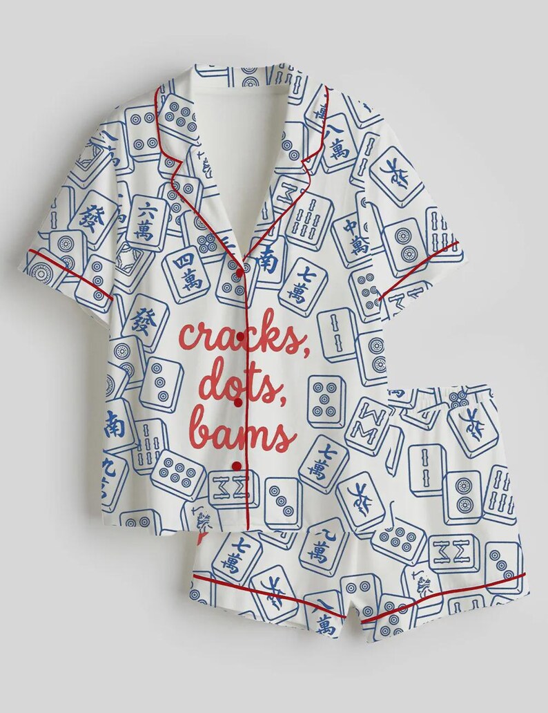 May include: White pajama set with a pattern of blue Mahjong tiles and red trim. The set includes a short-sleeved button-up shirt and matching shorts. The words "cracks, dots, bams" are printed in red on the shirt.