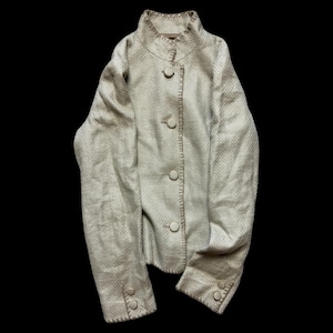 Puede incluir: Chaqueta beige claro con tejido texturizado. La chaqueta tiene cuello alto, tres botones delanteros y botones en los puños. La chaqueta es de color neutro y tiene un corte entallado. Mide unos 60 cm de largo.