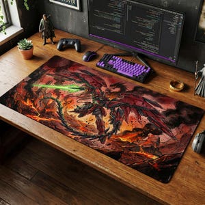 May include: Large rectangular mouse pad featuring a detailed illustration of a red and black mech-like figure with large wings, a green energy blade, and a dragon. The background is a fiery landscape. A purple keyboard and mouse are visible.