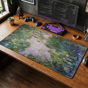 Puede incluir: Alfombrilla de escritorio rectangular con una pintura de nenúfares en tonos verdes, azules y rosas. La obra de arte recuerda al impresionismo. La alfombrilla está colocada sobre un escritorio de madera, con un teclado y un ratón visibles.