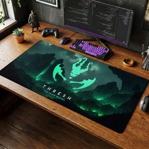 May include: A large rectangular black and green gaming mousepad with the text "THRESH The Chain Warden". The design features a stylized green graphic over a mountain and forest landscape.