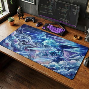 Puede incluir: Una alfombrilla de escritorio rectangular que presenta una vibrante ilustración artística de un gran fénix azul gélido con las alas extendidas, rodeado de nubes arremolinadas, fragmentos cristalinos y un fondo cósmico azul profundo y estrellado con toques morados.