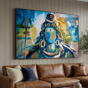 May include: Large framed artwork depicting a deity with a blue face, adorned with gold accents and a trident. The painting features a vibrant colour palette of blues, greens, and gold, creating a striking visual impact. The artwork is displayed above a brown leather sofa.