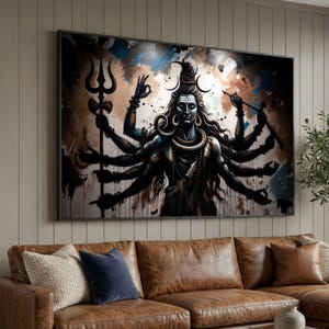 Op de afbeelding: Een ingelijste canvas print van een veelarmige godheid met een serene uitdrukking. Het kunstwerk heeft een donker kleurenpalet met blauwe, bruine en witte accenten. De godheid houdt verschillende objecten vast en is omgeven door abstracte penseelstreken. De print wordt weergegeven boven een bruine leren bank.