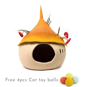 Può includere: Un letto per gatti in feltro beige a forma di fungo con un tetto in feltro giallo e arancione. Il letto ha un'apertura rotonda per consentire al gatto di entrare. Il tetto ha una punta appuntita ed è decorato con erba in feltro verde e funghi in feltro rosso. Il letto è su uno sfondo bianco. 4 palline giocattolo per gatti gratis.