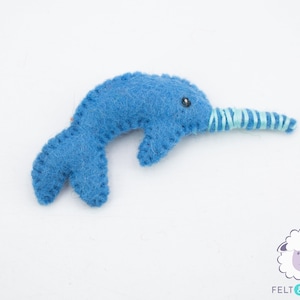 May include: A blue felt narwhal with a light blue and white striped horn. The narwhal is a popular children's toy.