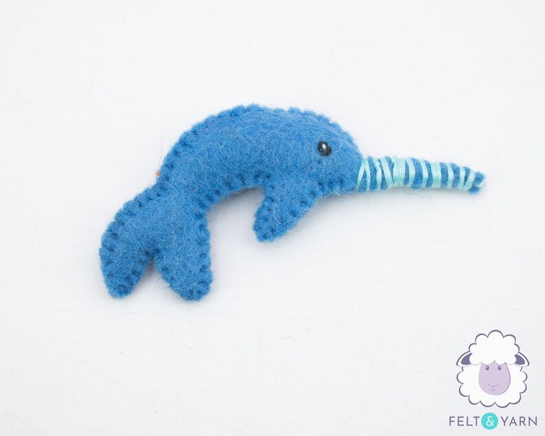 May include: A blue felt narwhal with a light blue and white striped horn. The narwhal is a popular children's toy.