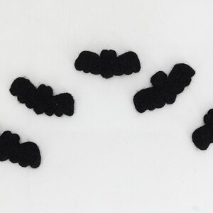 May include: Five black felt bats, each with a different shape and size, are arranged on a white background.