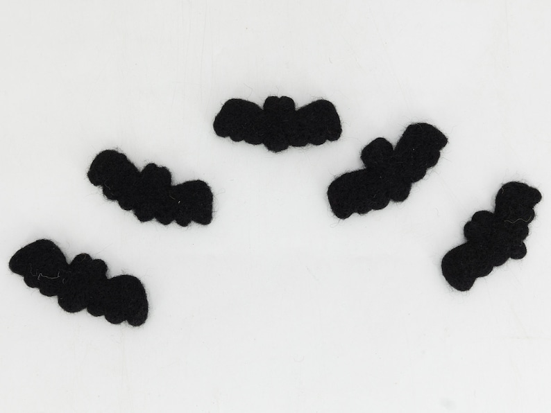 May include: Five black felt bats, each with a different shape and size, are arranged on a white background.