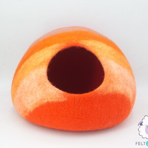 May include: Orange and white felted wool cat bed shaped like a dome with a round opening.