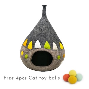 Puede incluir: Una cama para gatos de fieltro gris en forma de lágrima con detalles de fieltro de colores. La cama tiene una abertura redonda para que el gato pueda entrar. Se incluyen cuatro bolas de fieltro de colores.