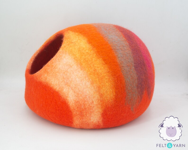 May include: Orange, yellow, pink and grey felt cat bed shaped like a dome with a round opening.