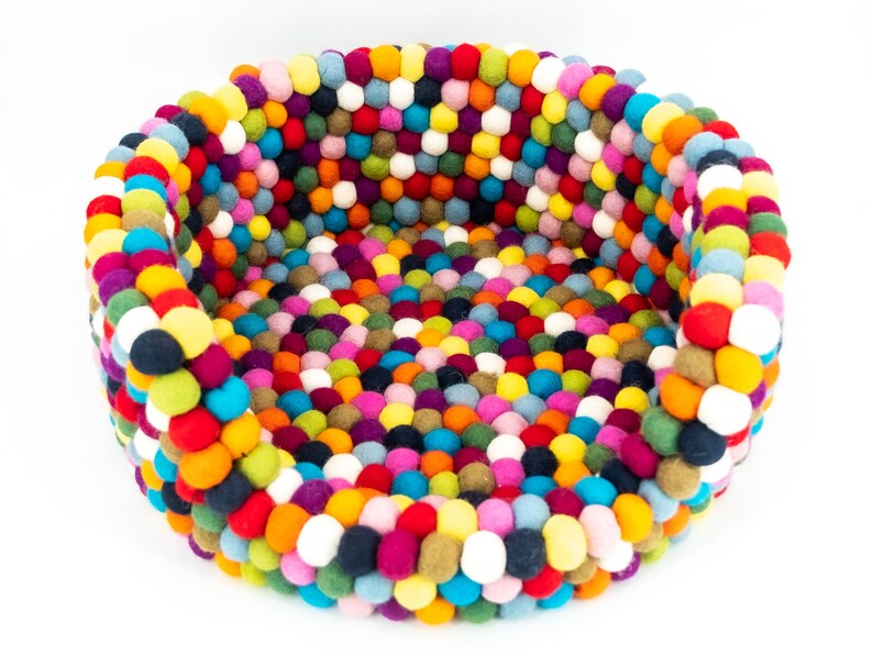 Pu&ograve; includere: Un letto rotondo per animali domestici colorato fatto di palline di feltro. Il letto &egrave; pieno di una variet&agrave; di colori, tra cui rosso, arancione, giallo, verde, blu, viola e bianco.