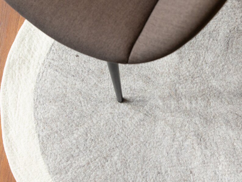 May include: A gray and white round rug with a single black chair leg in the center.