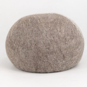 May include: A large, round, gray and white felt pouf ottoman. The pouf is made of a soft, fuzzy material and has a slightly textured surface.