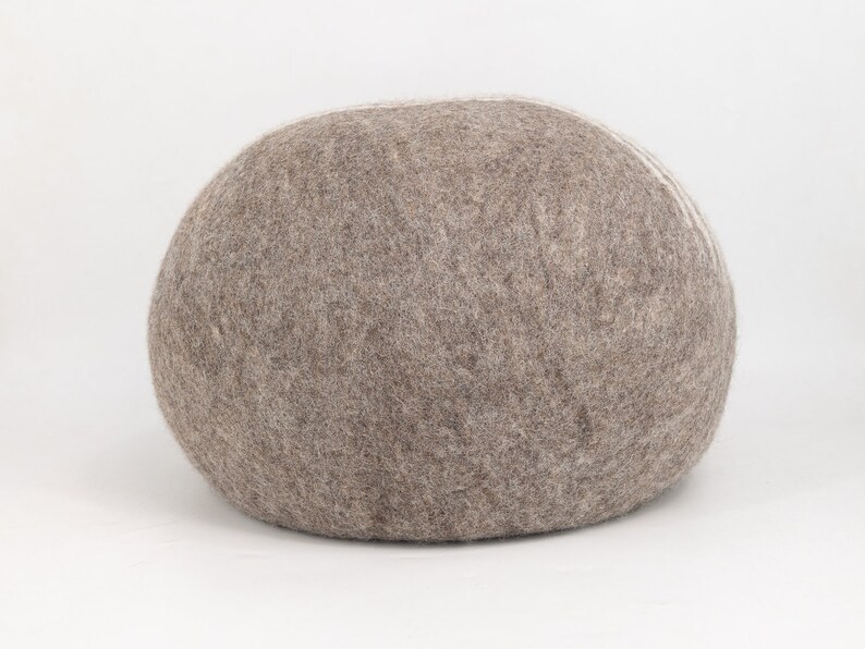 May include: A large, round, gray and white felt pouf ottoman. The pouf is made of a soft, fuzzy material and has a slightly textured surface.