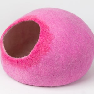 May include: A pink felt cat bed shaped like a dome with a large opening for entry. The bed is made of soft, fuzzy felt and is perfect for small pets.
