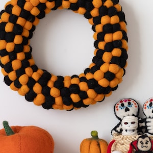 Puede incluir: Una corona de Halloween hecha de bolas de fieltro naranja y negro. Tambi&eacute;n hay dos esqueletos de fieltro, una calabaza de fieltro y un vampiro de fieltro.