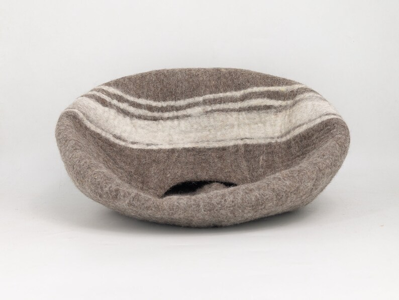 May include: A brown felt bowl with white stripes. The bowl is shaped like a half-sphere and has a hole in the bottom.