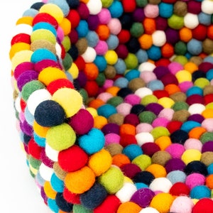 Pu&ograve; includere: Un letto rotondo per animali domestici colorato fatto di palline di feltro. Il letto &egrave; fatto di una variet&agrave; di colori, tra cui rosso, blu, verde, giallo, arancione, viola e bianco.